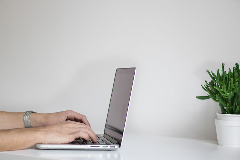 View of person's hands typing on laptop